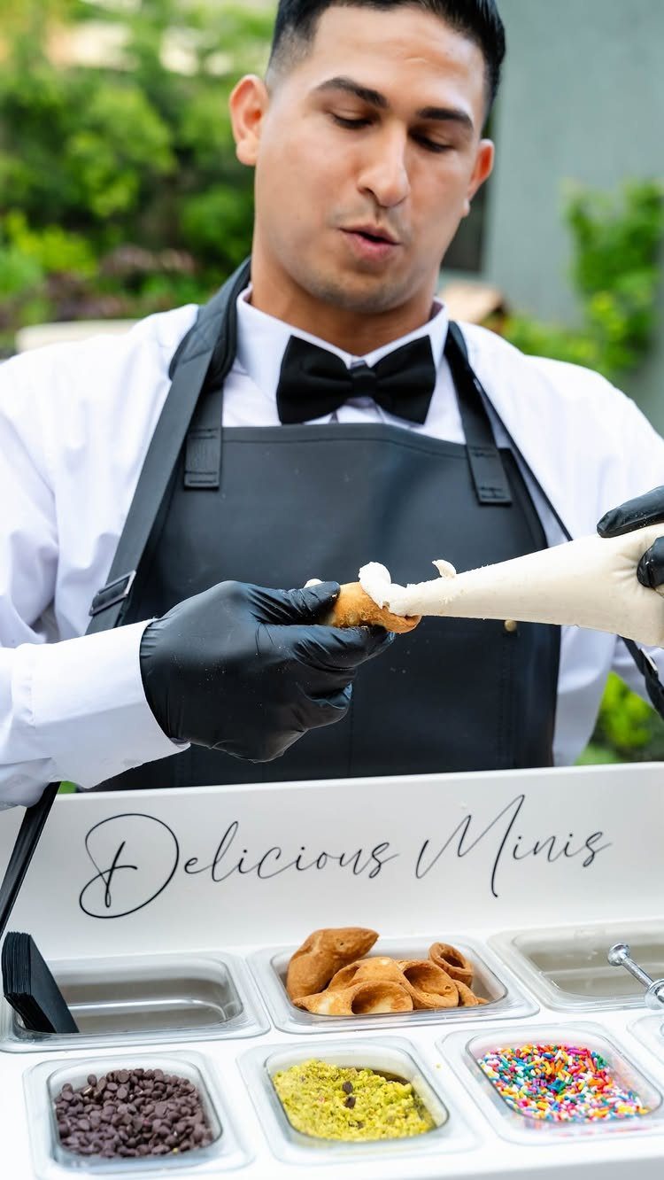 Chef piping cream into mini cones at an interactive dessert station with toppings.