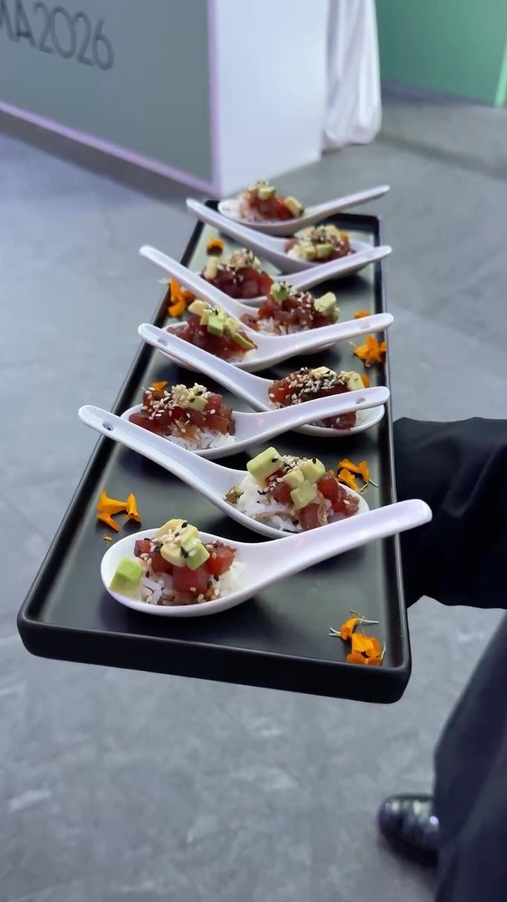 Tuna and avocado appetizers served on white spoons on a black tray