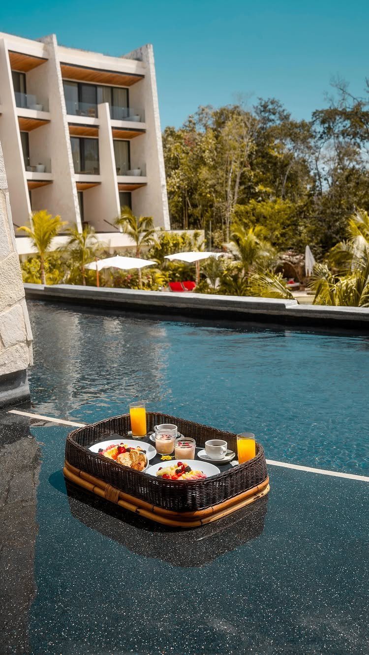 Floating breakfast tray in a luxury pool with a modern hotel in background