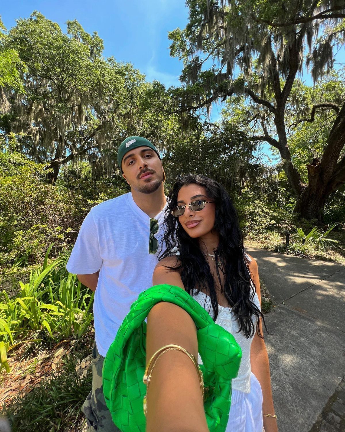Young couple posing for a selfie in a garden with mossy oak trees.