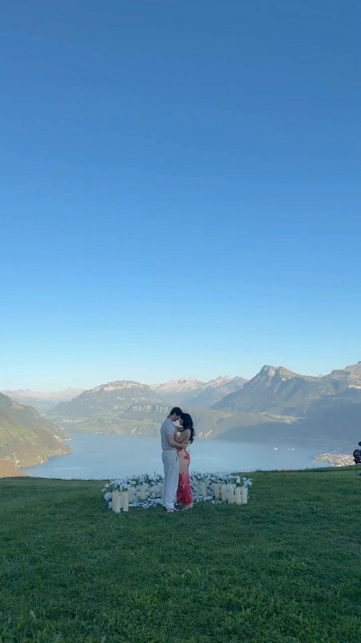 Couple embracing in a flower circle overlooking a lake and mountains at dusk.