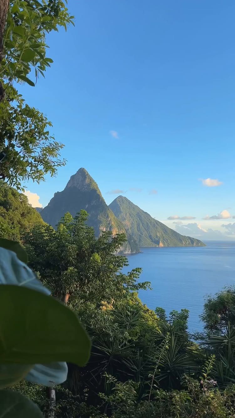 Lush green mountains meeting a blue ocean under a clear sky.