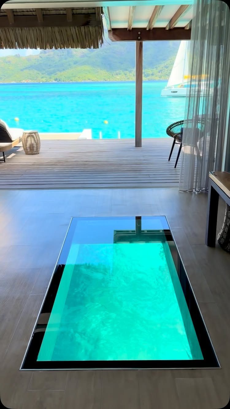 Overwater bungalow interior with a glass floor panel overlooking crystal-clear turquoise tropical waters.