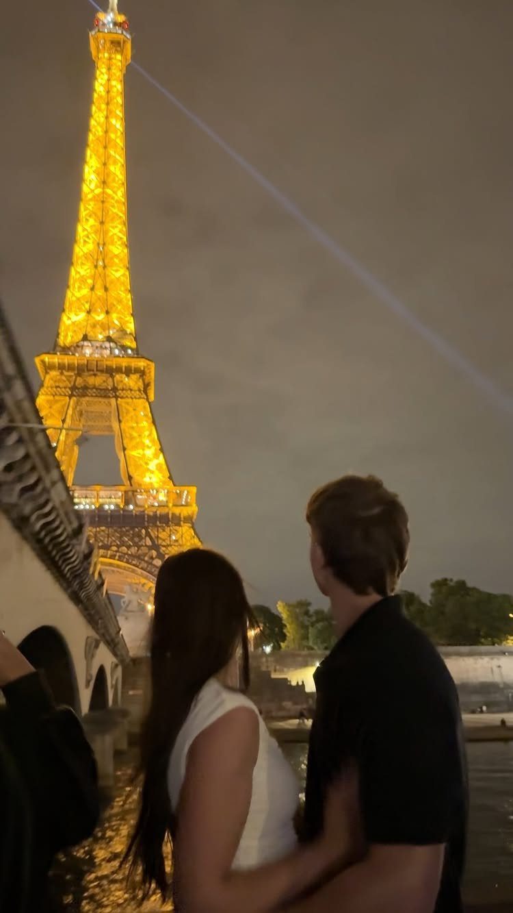Couple looking at the illuminated Eiffel Tower by the river at night