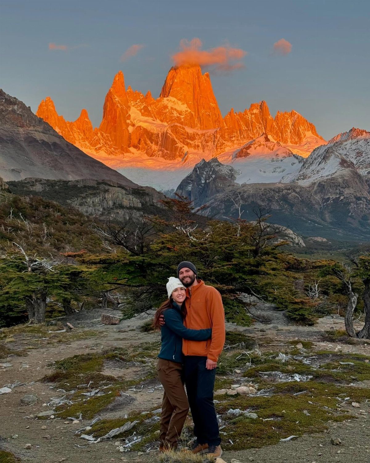 Couple embracing in front of the glowing orange peaks of Patagonia, Chile mountains.