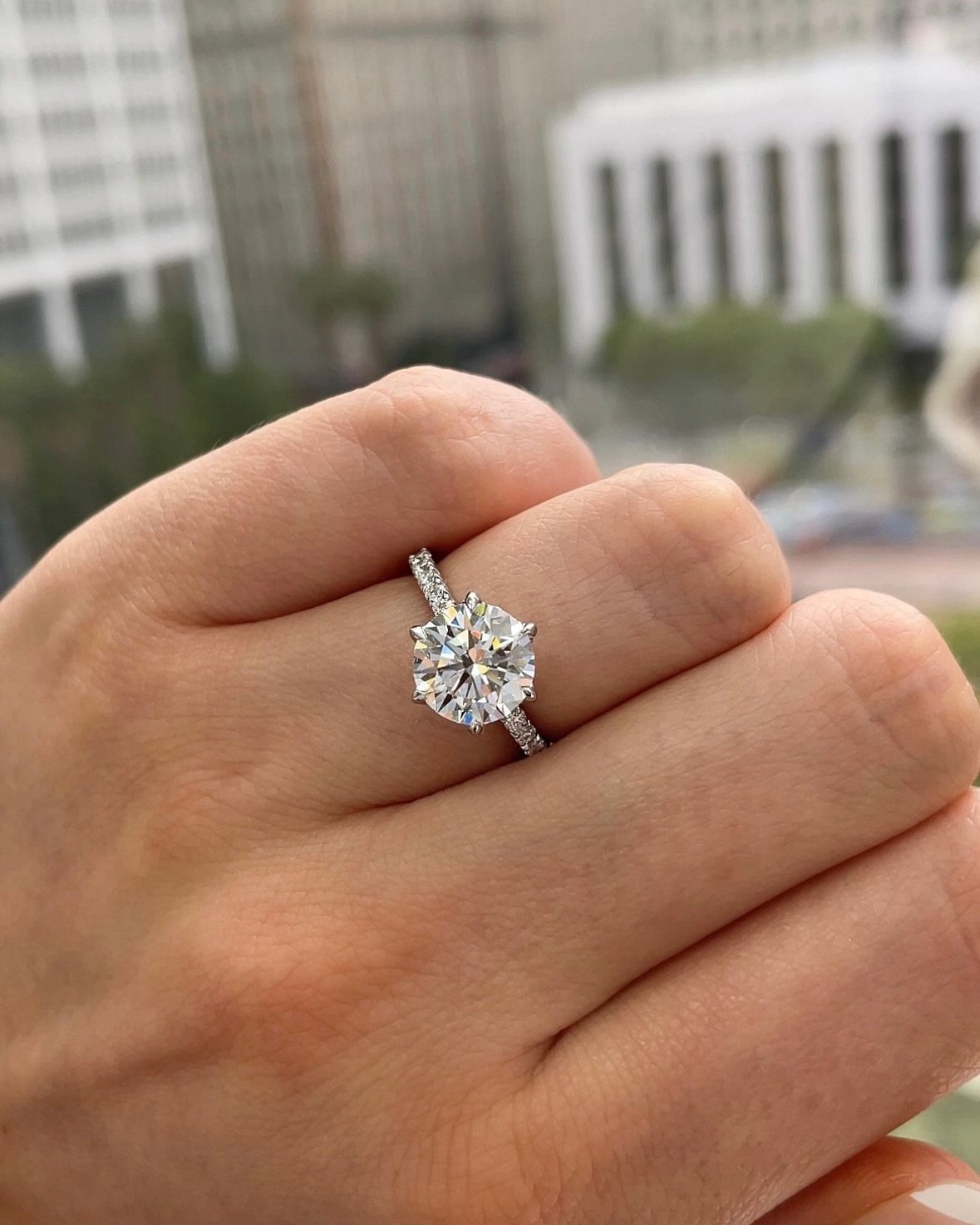 Diamond engagement ring with a round center stone on a person's finger.