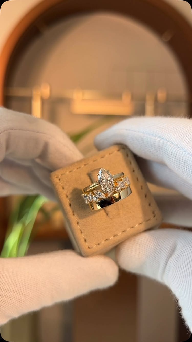 Yellow gold engagement ring with marquise diamond in a tan velvet box.