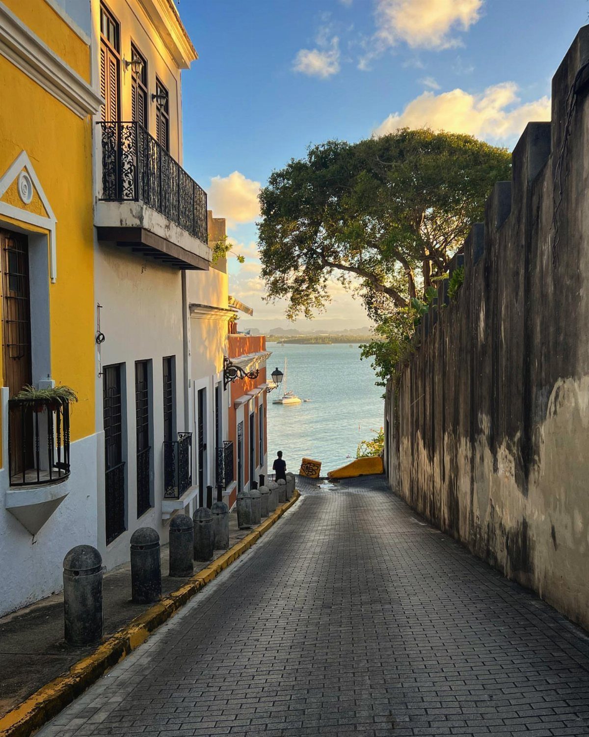 Cobblestone street in Old San Juan leading toward the blue ocean bay.
