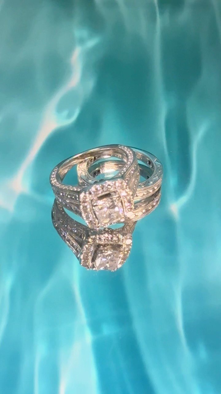 Two diamond wedding rings reflecting on a shimmering turquoise water-like surface.