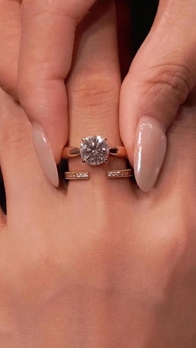 Rose gold engagement ring and matching wedding band on a person's finger.