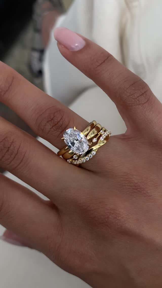 Stack of gold rings with a large oval diamond on a finger