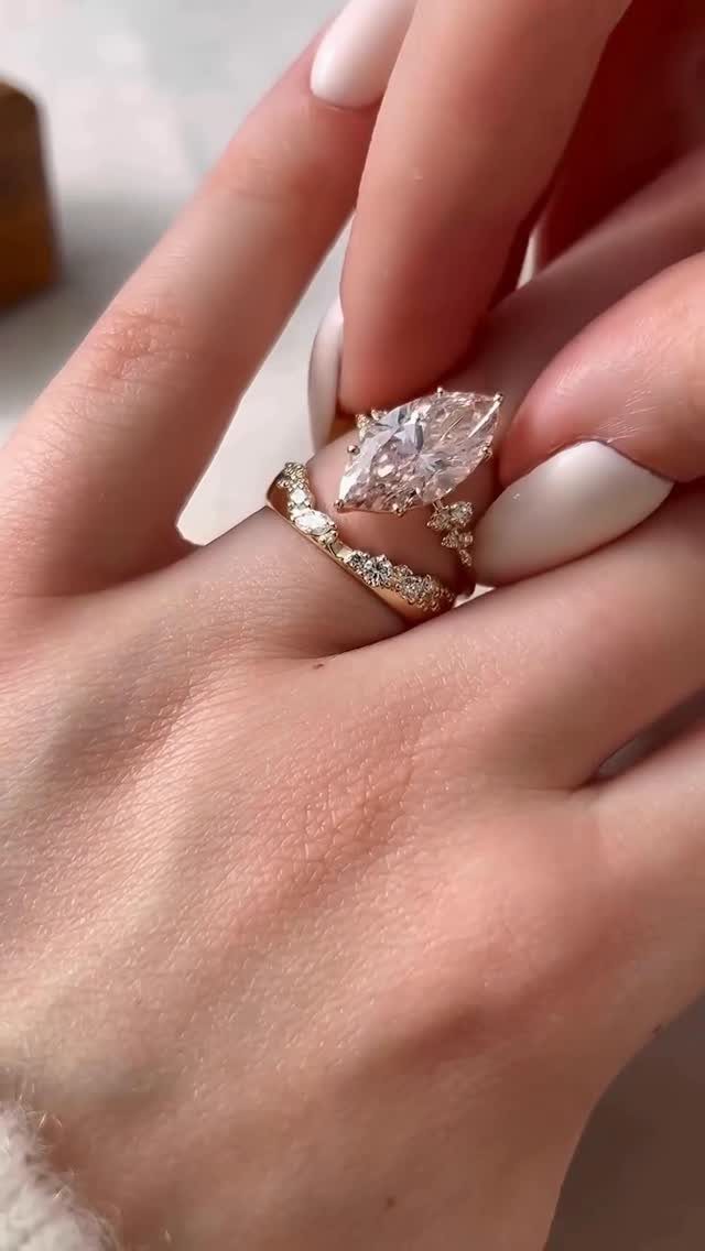 Three gold diamond rings stacked on a finger with white manicured nails.