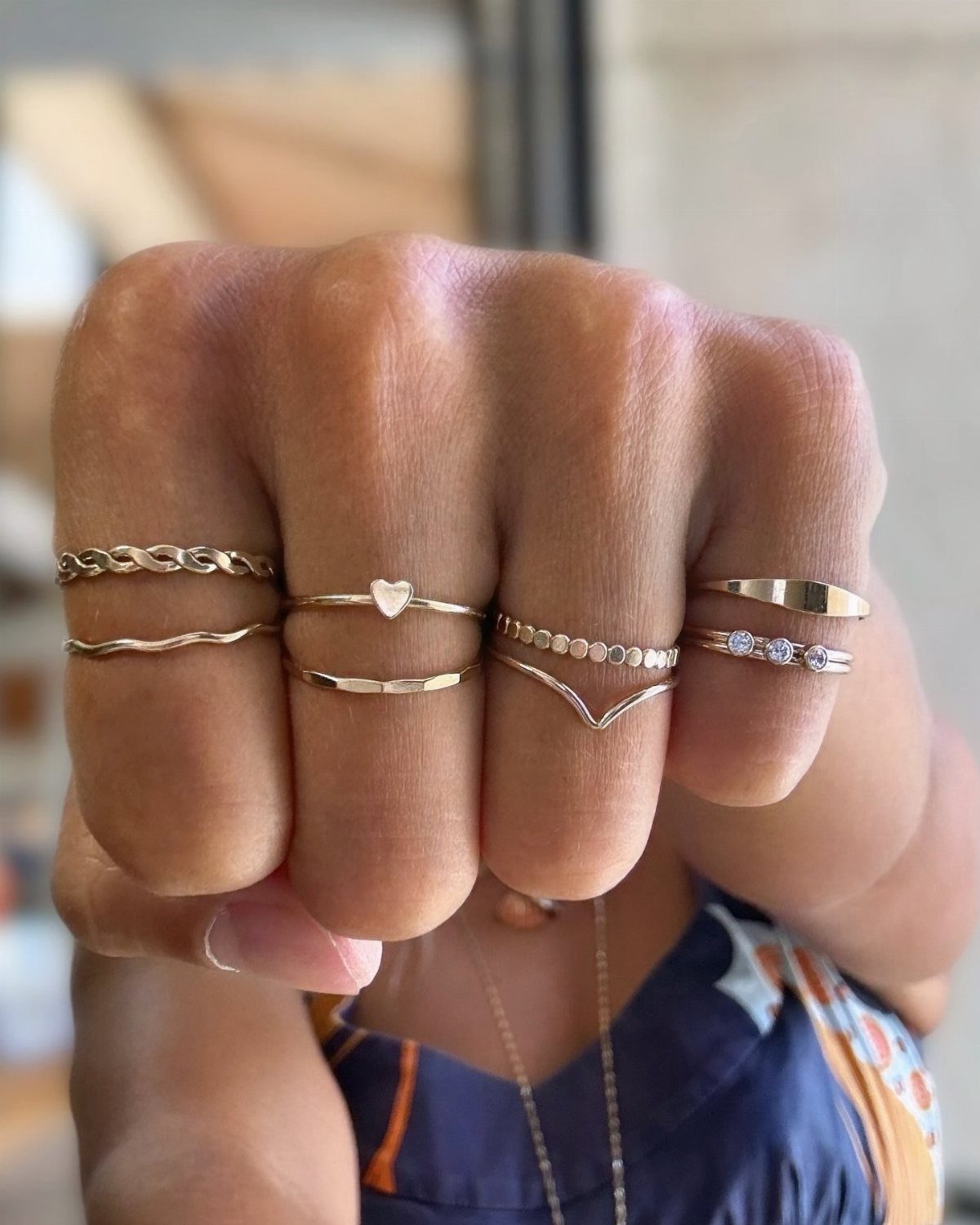 Gold stackable rings on fingers, including a heart band and diamond accents.