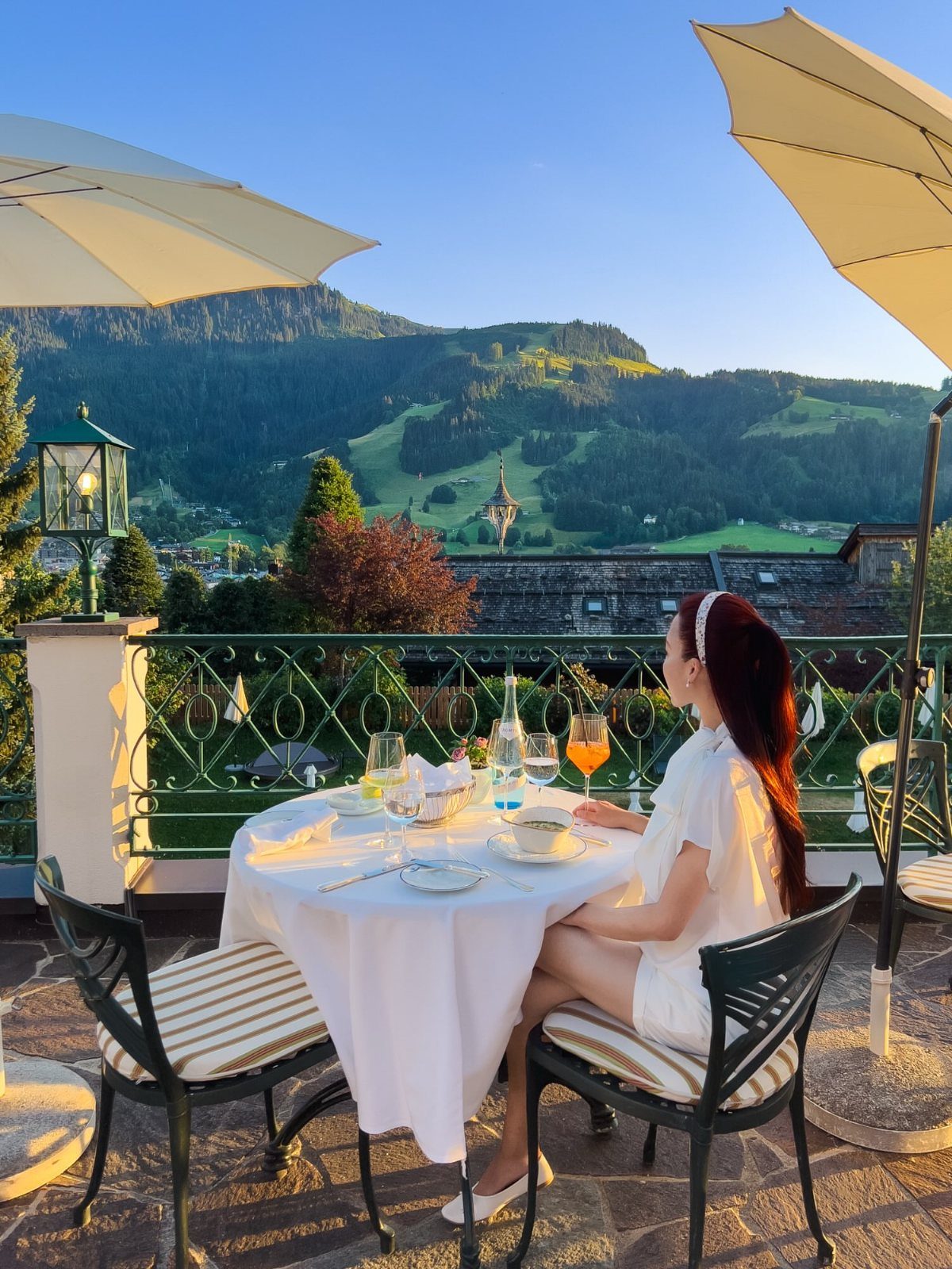 Woman dining on a terrace overlooking a village in the Bavarian Alps mountains.