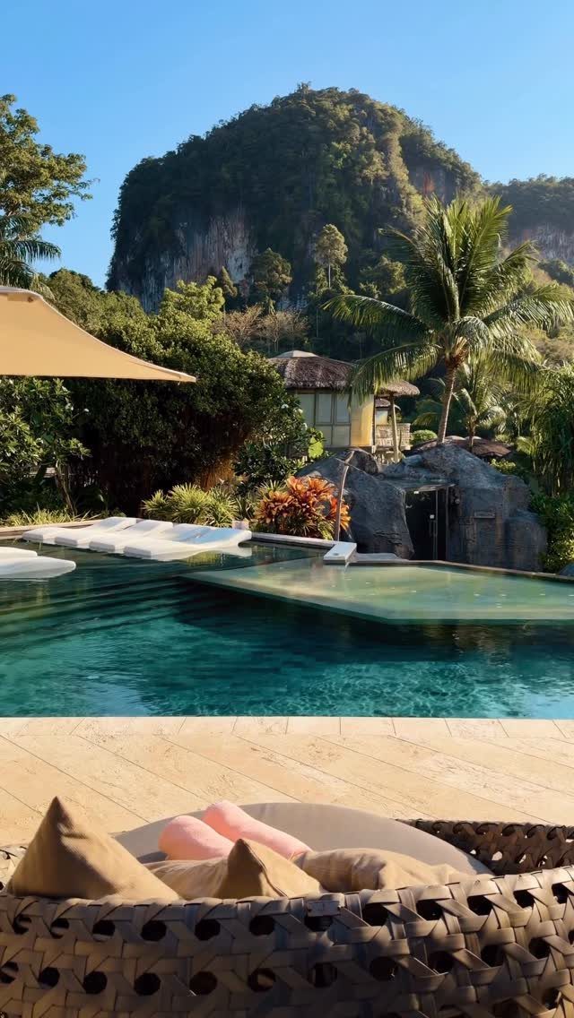 Luxury resort pool with turquoise water and a limestone cliff in the background.