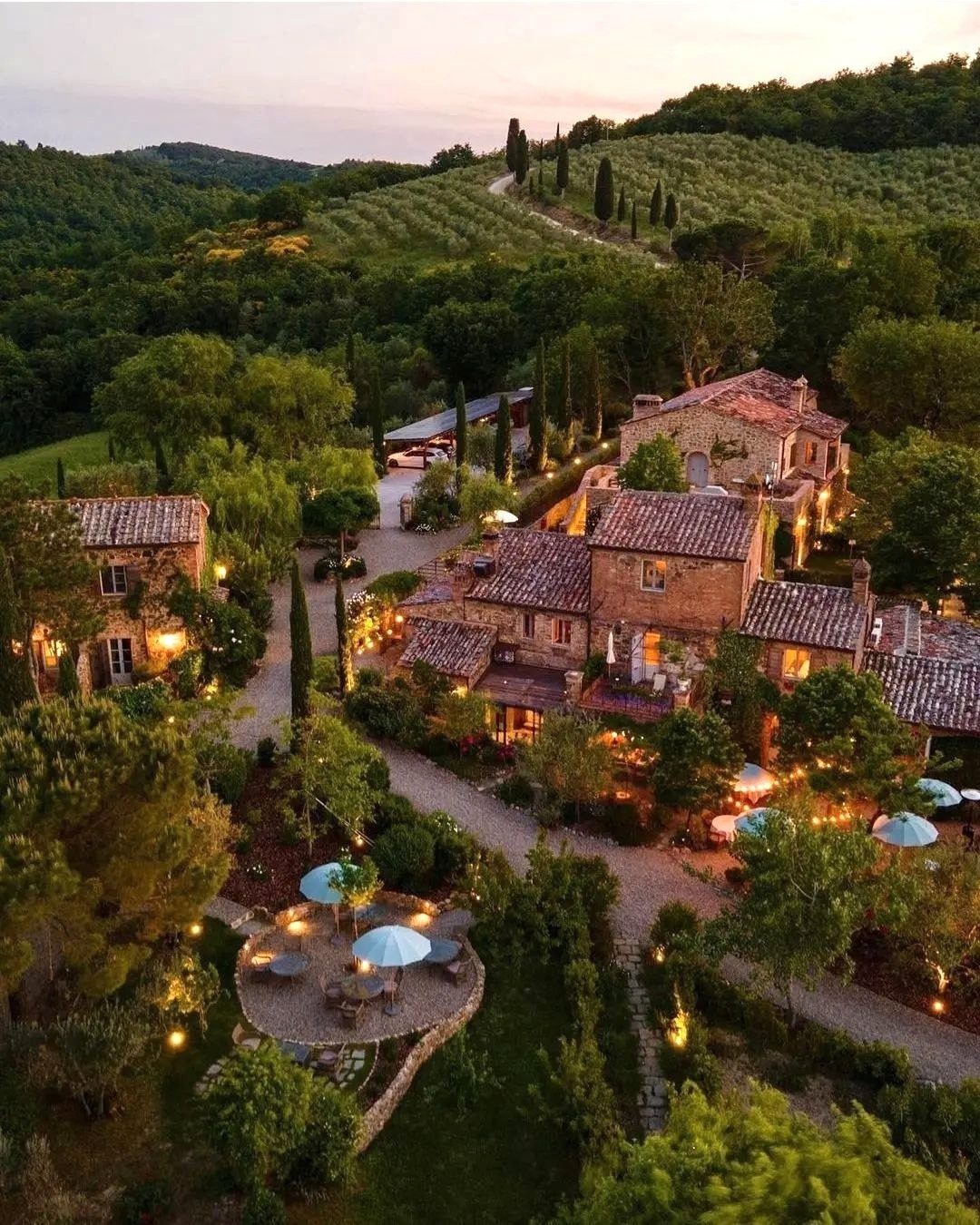 Rustic stone village with terracotta roofs nestled among lush green rolling hills.