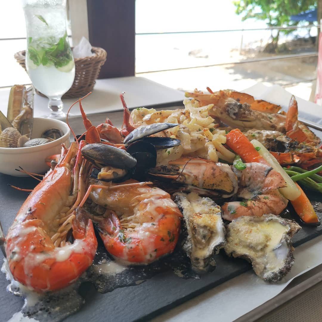 Seafood platter with prawns, mussels, and oysters on a slate board by the beach
