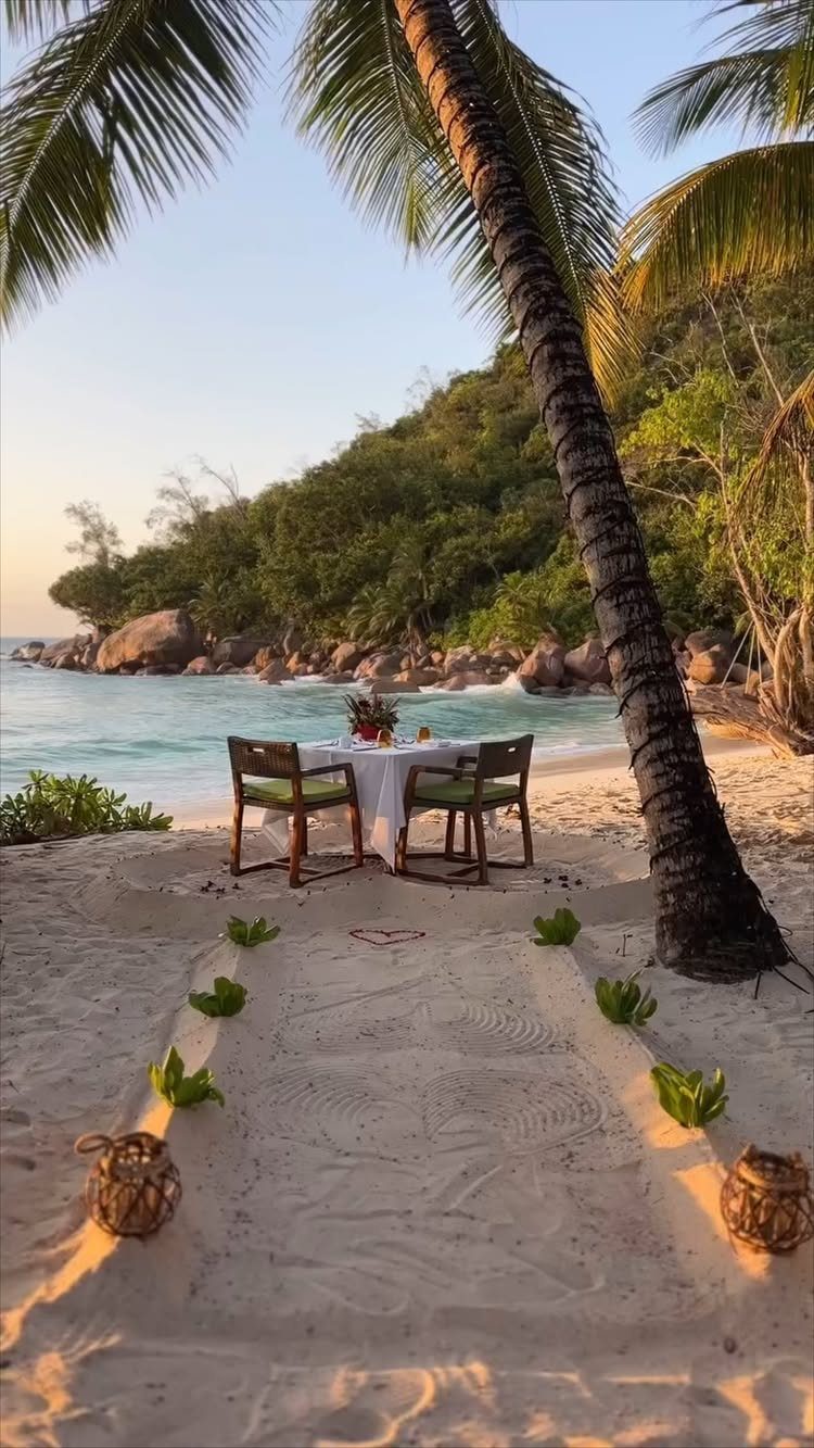 Romantic dinner table for two on a tropical beach with palm trees and turquoise water