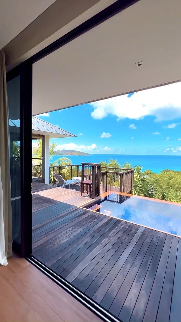 Luxury tropical villa deck with infinity pool overlooking a turquoise ocean coastline.
