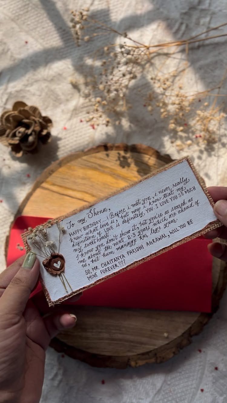 Handwritten love letter on aged paper with a small heart and dried flowers.