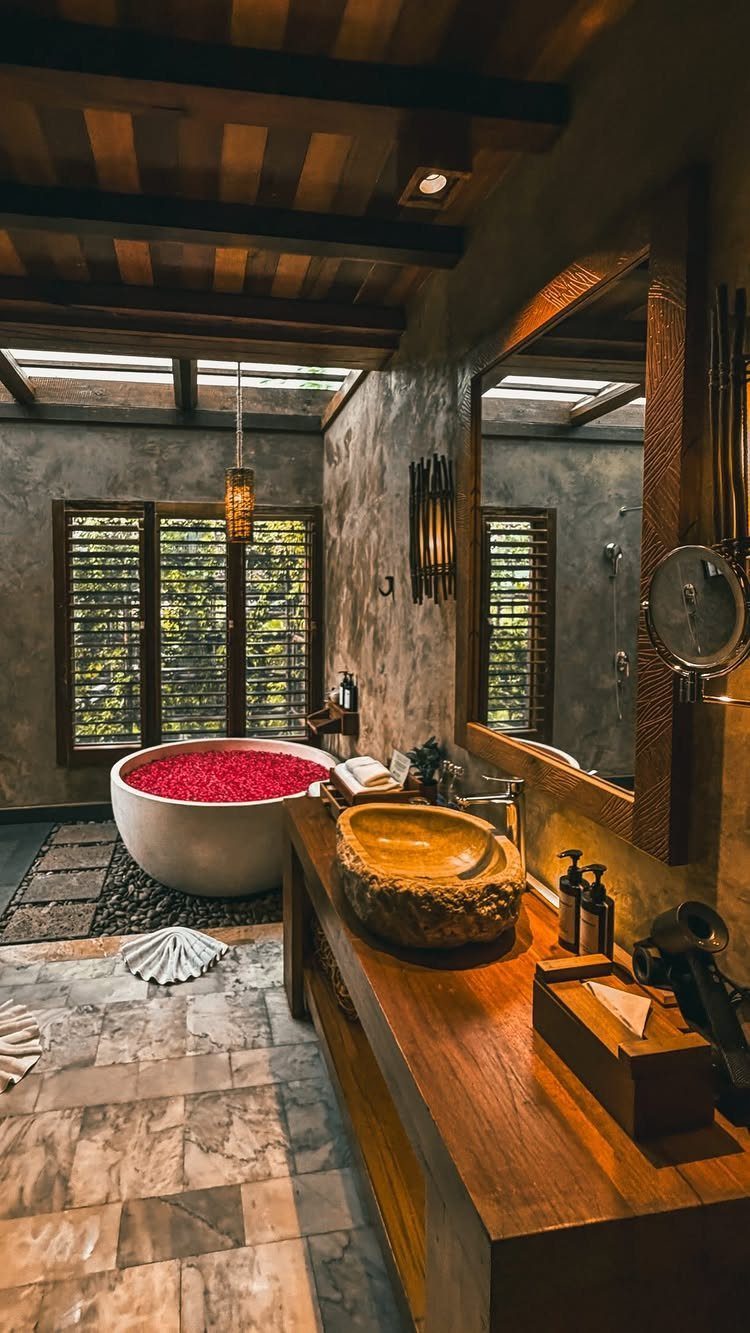 Luxury bathroom with a petal-filled bathtub and carved stone sink in tropical style