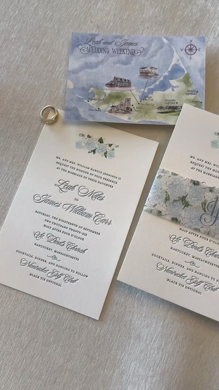 White wedding invitations with blue floral designs, a watercolor map, and a gold ring.