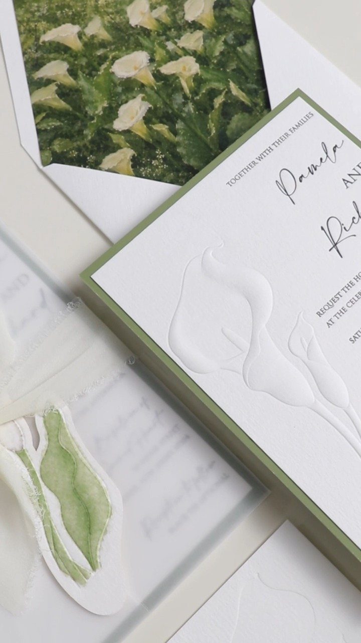 Wedding invitation suite with embossed calla lilies and a floral print envelope liner.