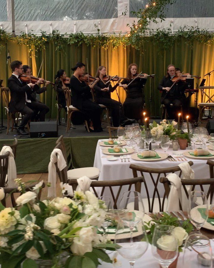 String quartet performing on a stage behind elegantly set wedding reception tables.