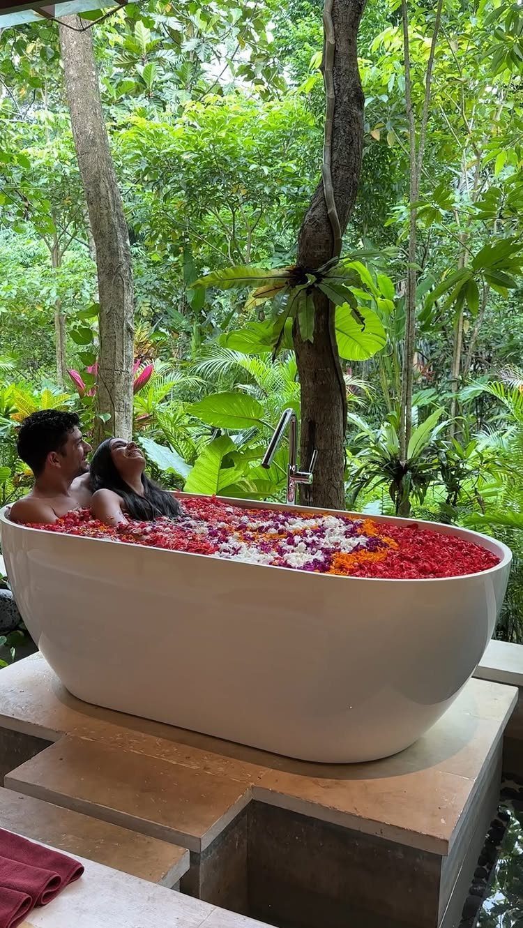 Couple relaxing in a flower petal bath surrounded by lush tropical greenery