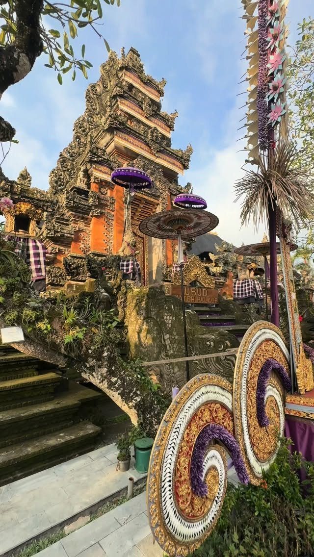 Ornate Balinese temple with traditional purple umbrellas and intricate stone carvings in Ubud.