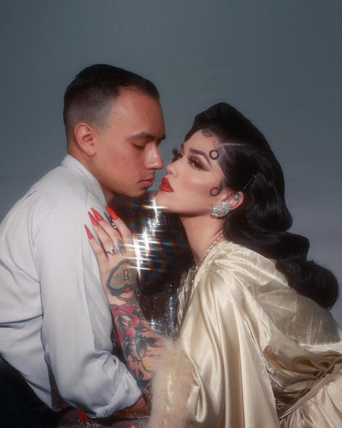 Couple posing closely, woman featuring vintage finger wave hairstyle and satin dress.