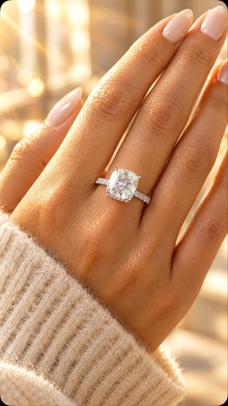 Diamond engagement ring on a hand with pink nails in warm golden light