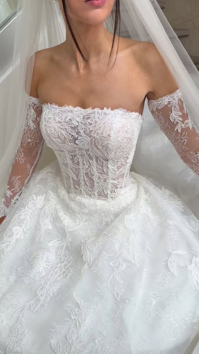 White lace wedding dress with separate off-the-shoulder sleeves and a sheer veil.