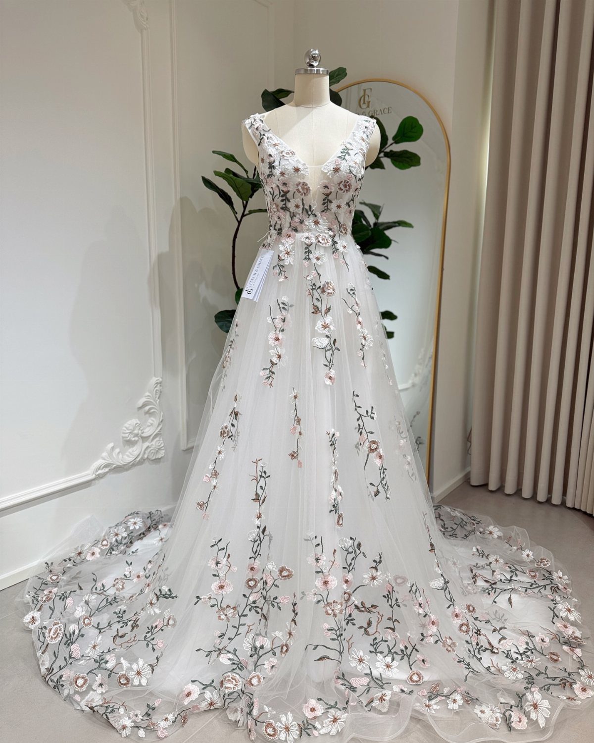 White A-line wedding dress with pink and green floral embroidery on a mannequin