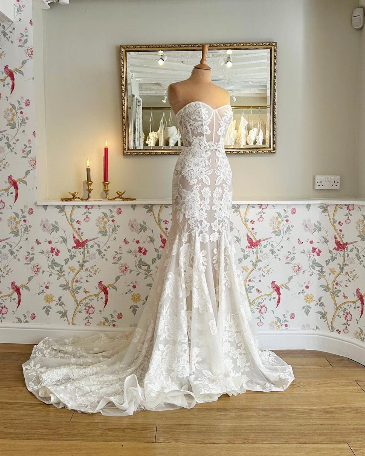 White lace mermaid wedding dress on a mannequin against floral wallpaper
