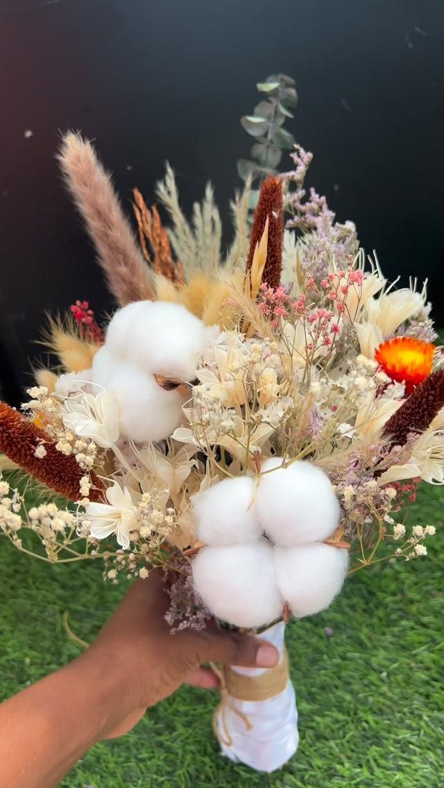 Dried flower bouquet with cotton bolls and pampas grass held by a hand.