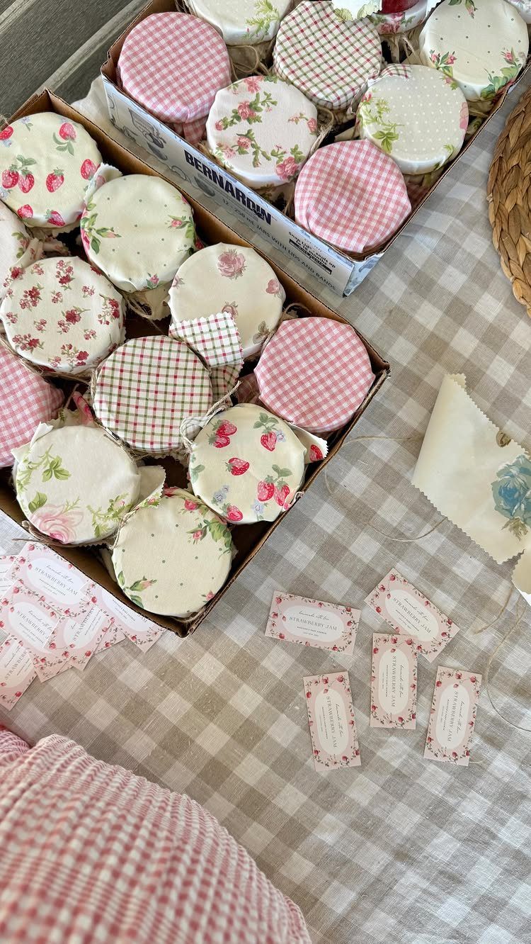 Small jam jars with floral fabric lids arranged on a checkered tablecloth.