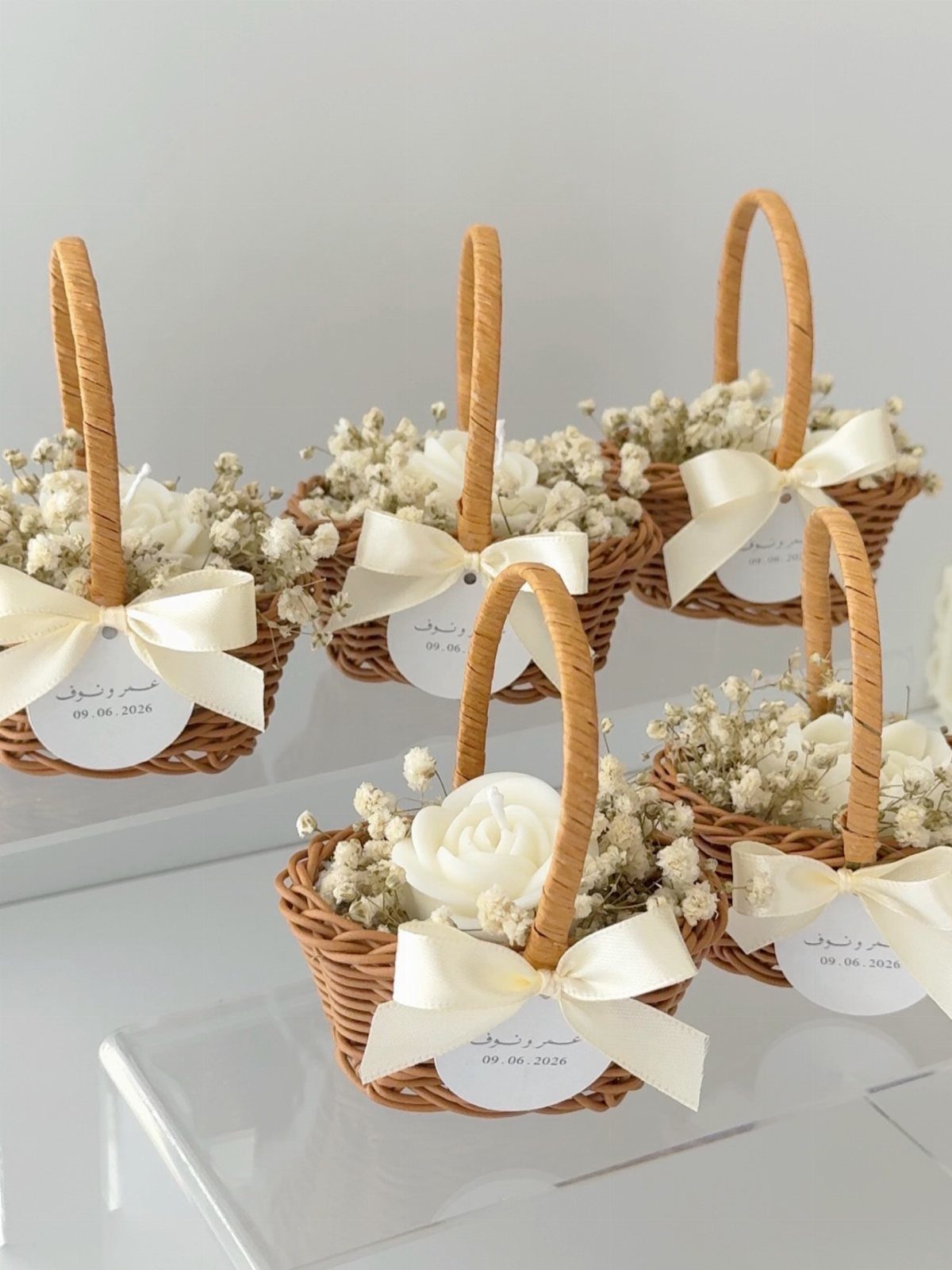 Small wicker baskets filled with white baby's breath and roses with satin bows.