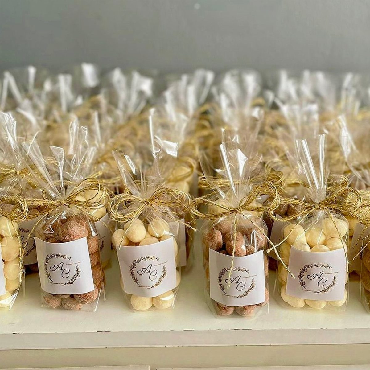 Clear bags of cookies tied with gold bows and personalized floral labels.