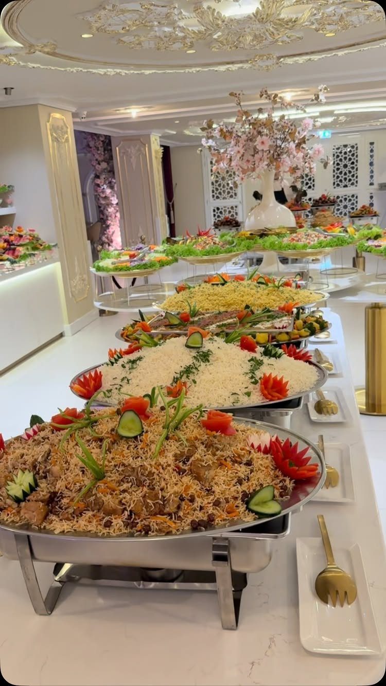 Buffet line with silver platters of rice and salads in an elegant room.