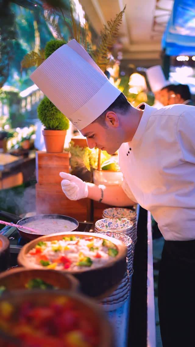 Chef in white uniform preparing colorful vegetable dishes at an outdoor catering station