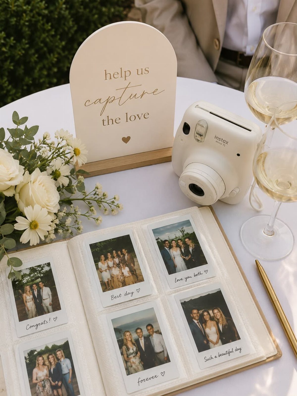 White Instax camera and guestbook with instant photos on a wedding table.