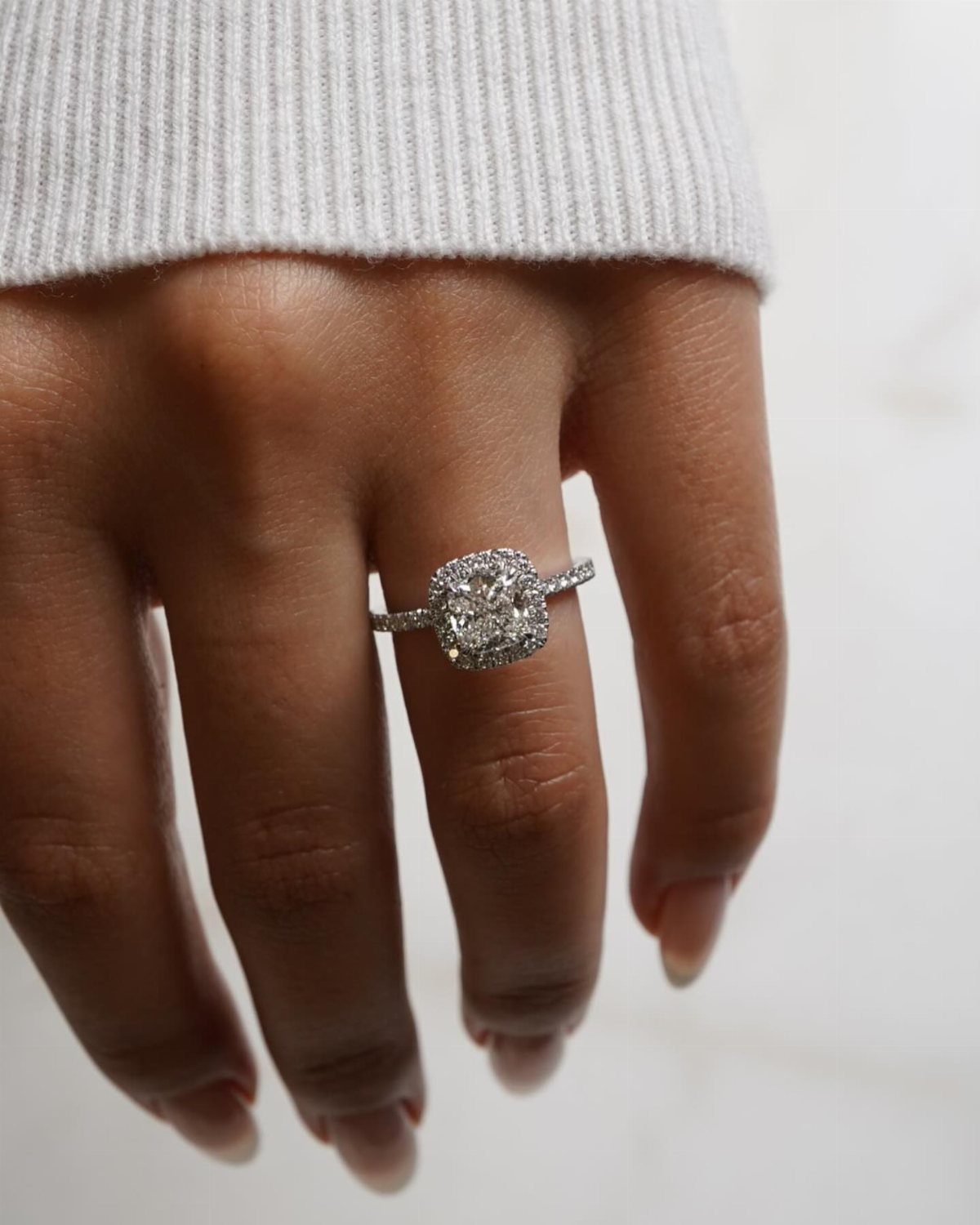 Diamond engagement ring with halo setting worn on a person's ring finger
