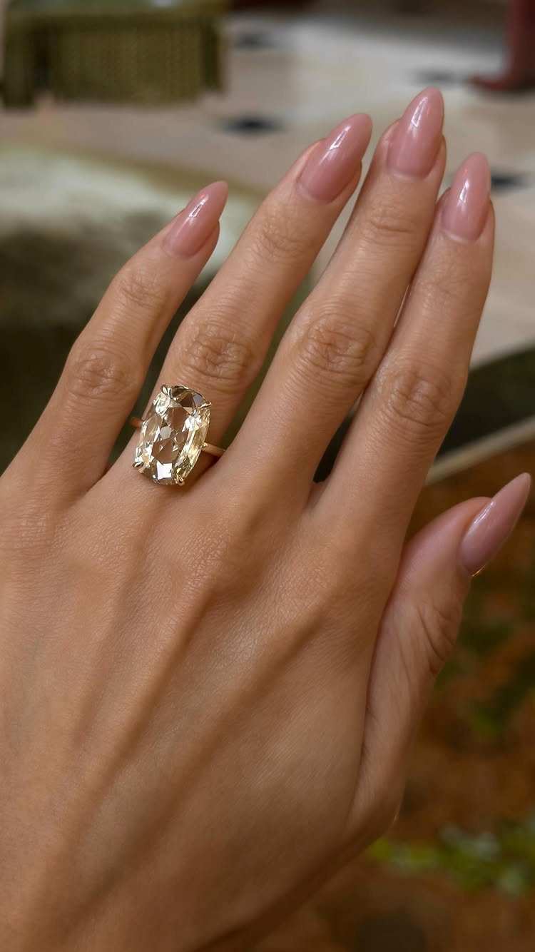 Gold ring with a large champagne diamond on a hand with pink nails