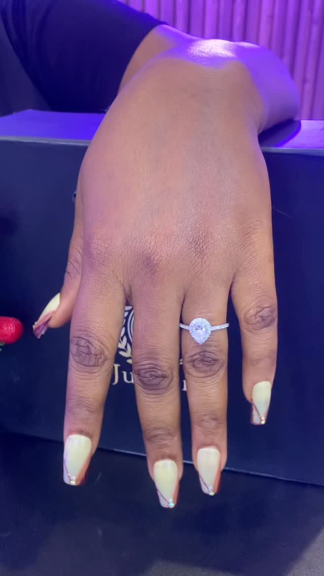 Hand wearing a silver ring with a clear pear-shaped moissanite gemstone