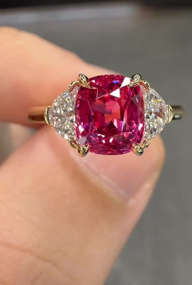 Gold ring with a large magenta-red cushion-cut gemstone and side diamonds