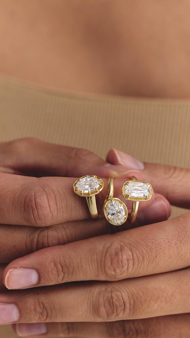 Three gold diamond rings with oval and emerald cuts on a hand