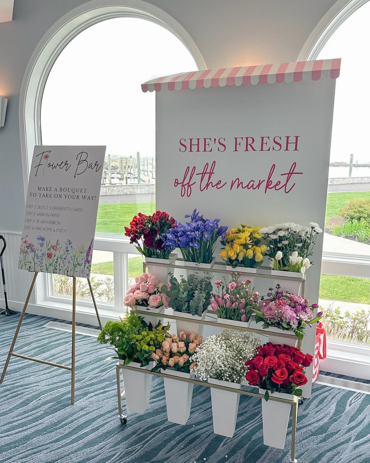 Flower bar setup with colorful blooms in white buckets and a themed backdrop.