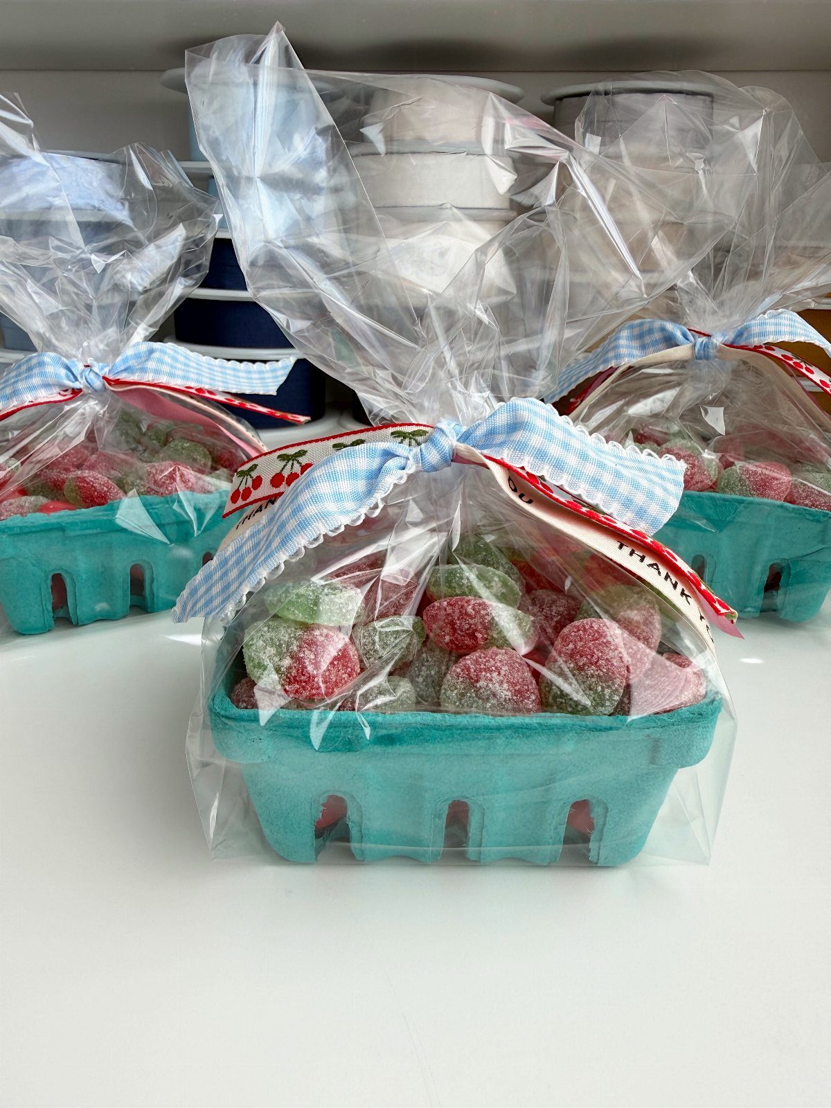 Turquoise berry baskets filled with red and green candies wrapped in cellophane ribbons.