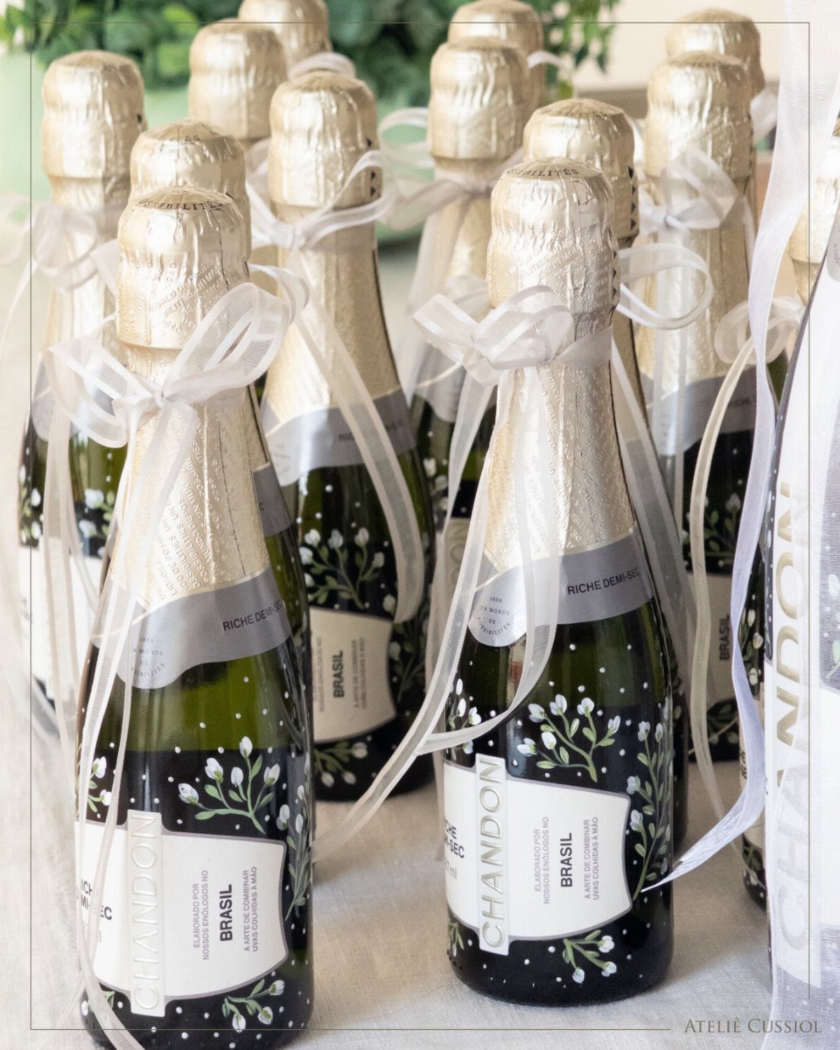 Mini bottles of champagne with gold foil and white ribbons for wedding favors.